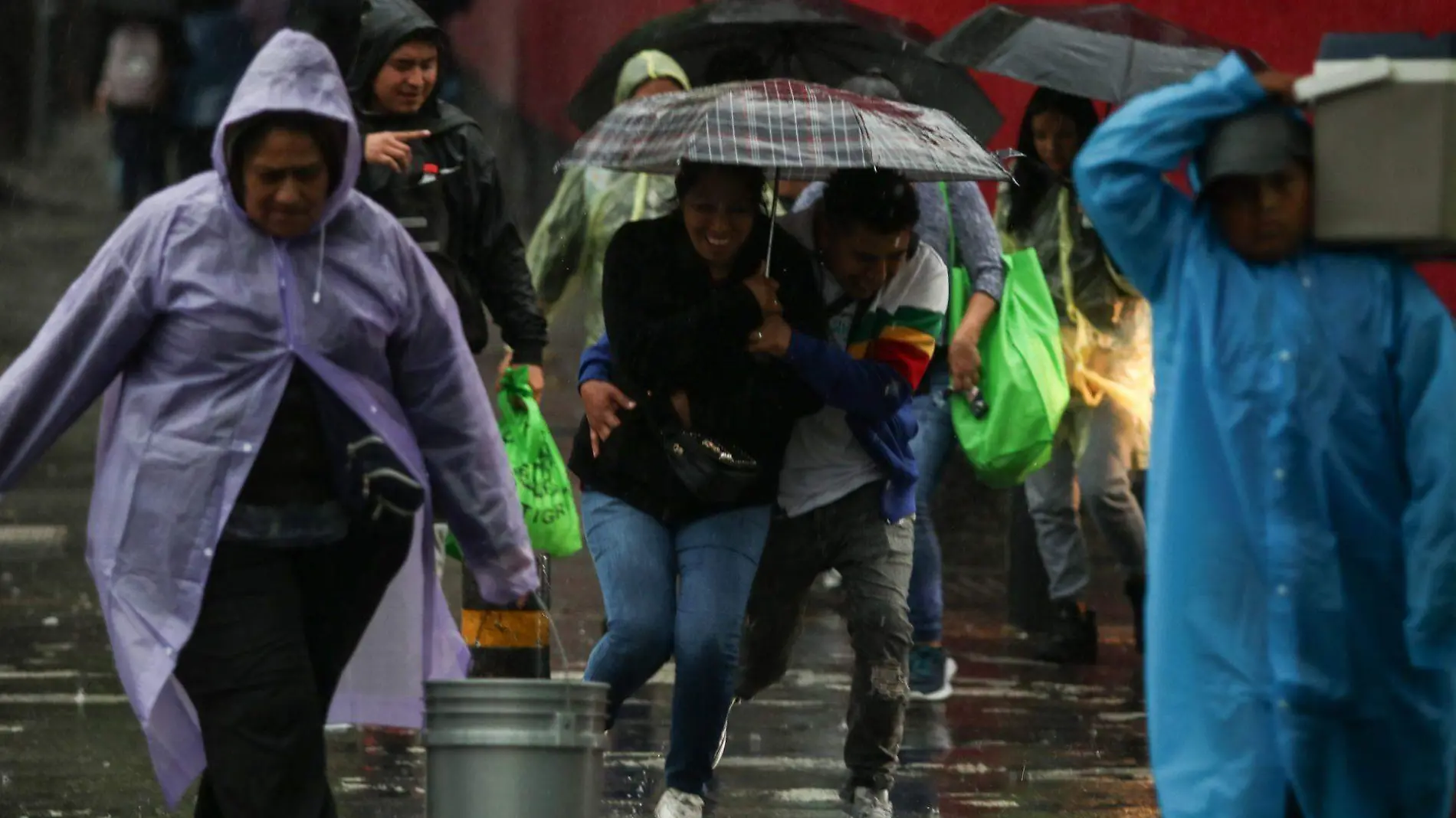 Población utilizando paraguas e impermeable